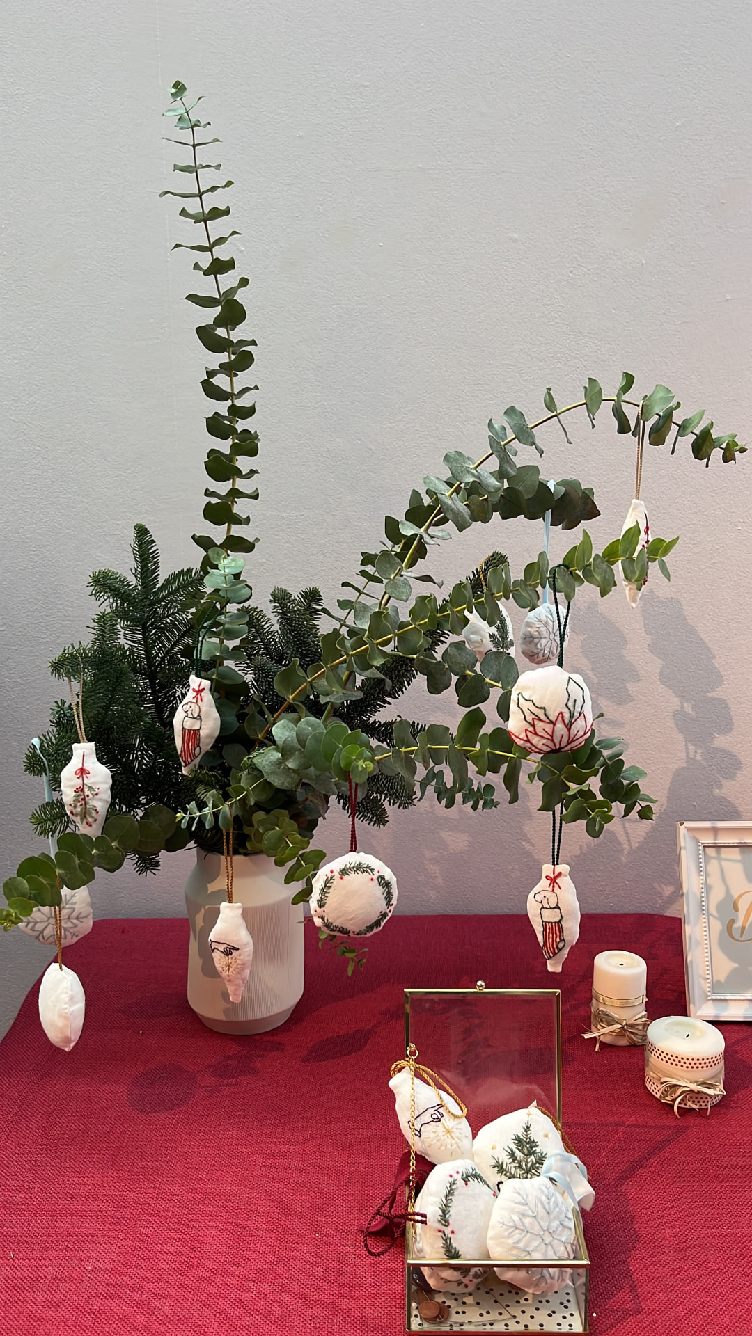Adornos navideños bordados entre ramas de eucalipto